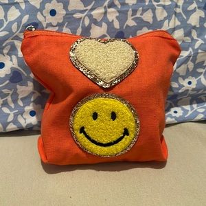 A cute mini orange bag with stickers perfect for small accessories and makeup.